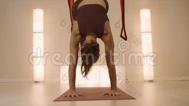 女人在空中<strong>瑜伽</strong>工作室练习<strong>瑜伽</strong>。 <strong>瑜伽</strong>教练站在<strong>垫</strong>子上双手站立